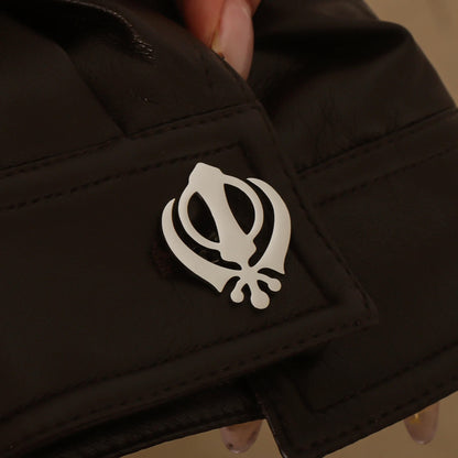 Silver Punjabi Sikh cufflink with Khanda emblem worn on a black leather cuff, showcasing stainless steel finish.