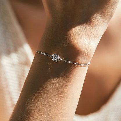 Silver bracelet with a central gemstone on a wrist against a blurred background